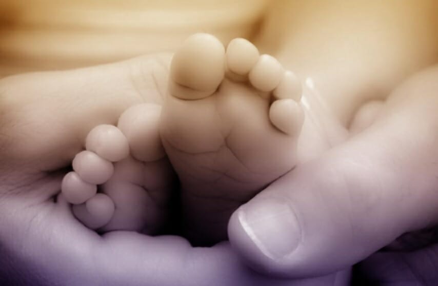 Close up shot of baby feet held by an adult hand
