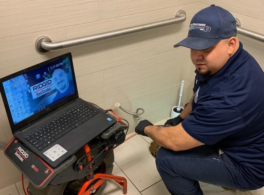 Flood Brothers employee working on a laptop in a bathroom